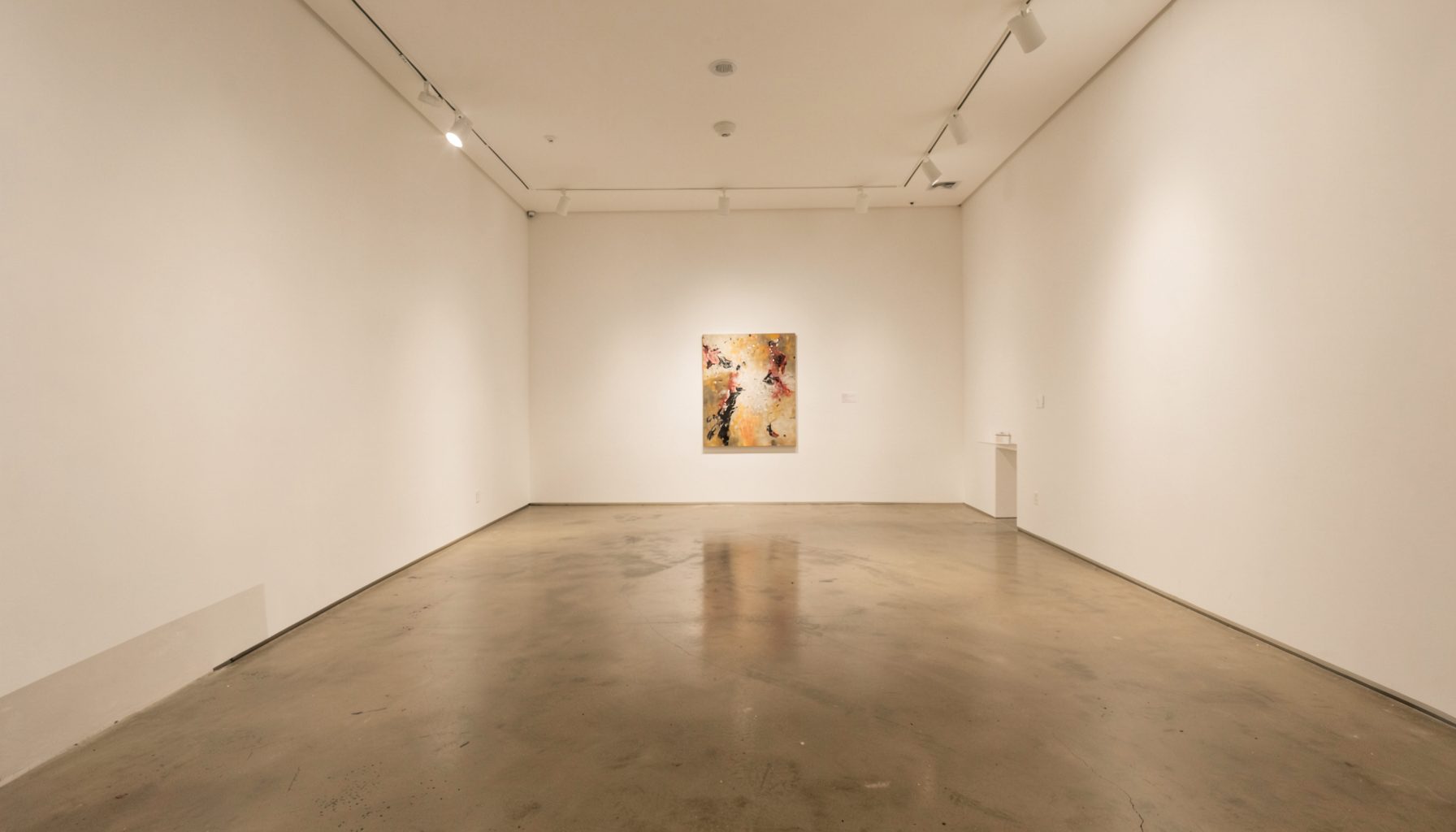 A softly lit gallery interior with white walls and a polished concrete floor, warm neutral tones, and an abstract painting visible in the distance.